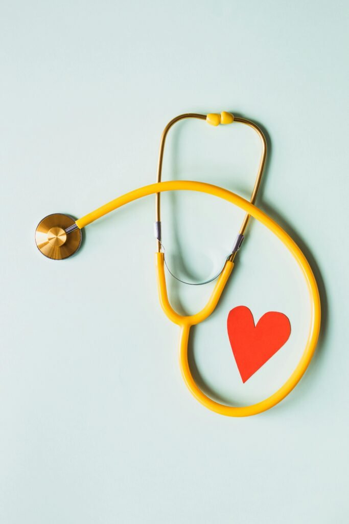 Home Yellow stethoscope arranged with a red heart cutout on a light green background, symbolizing heart health.