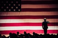 A solemn moment as a soldier salutes the American flag during a ceremony inside an auditorium.