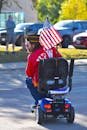 Veteran on Street Driving Mobility Scooter with American Flag