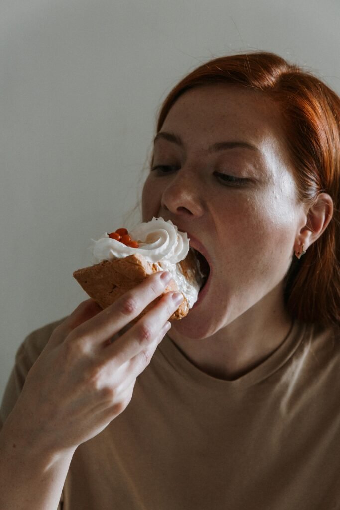 pexels photo 5491340 5491340 A woman indulges in a dessert slice with whipped cream and cherries.